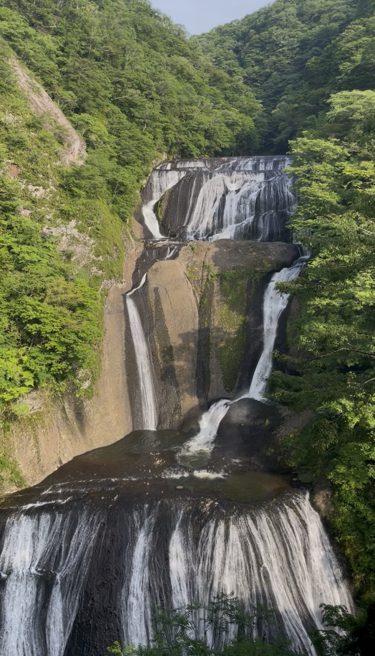 Fukuroda no Taki waterfall cascading down tiered rocky cliffs surrounded by green forest